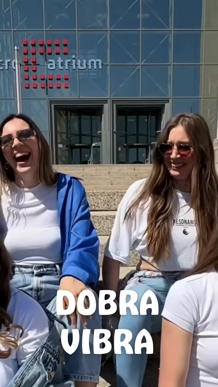 Frame from the V2 Training video: friends sitting on steps with the on-screen text “Dobra vibra”