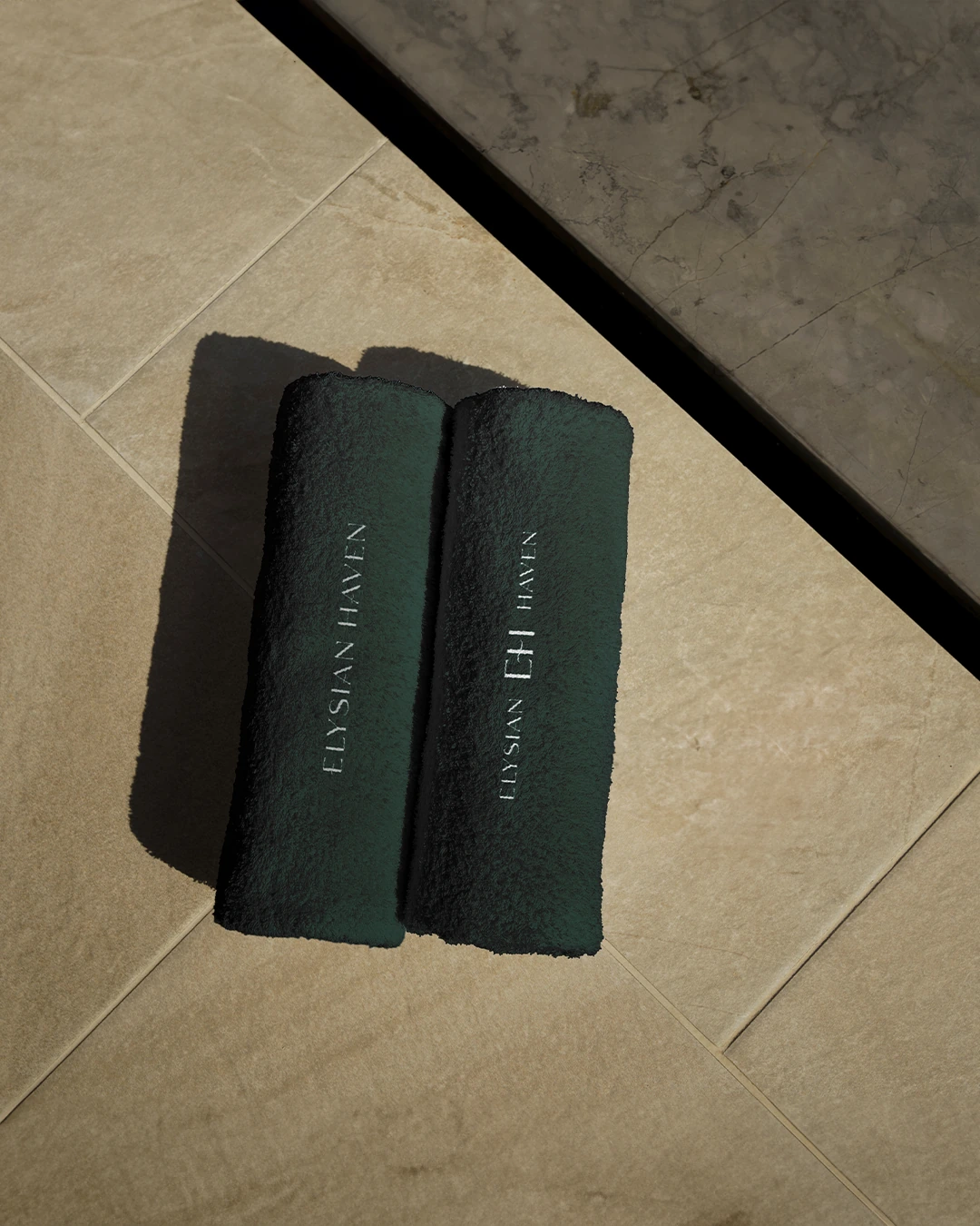 Two folded forest-green Elysian Haven branded towels
