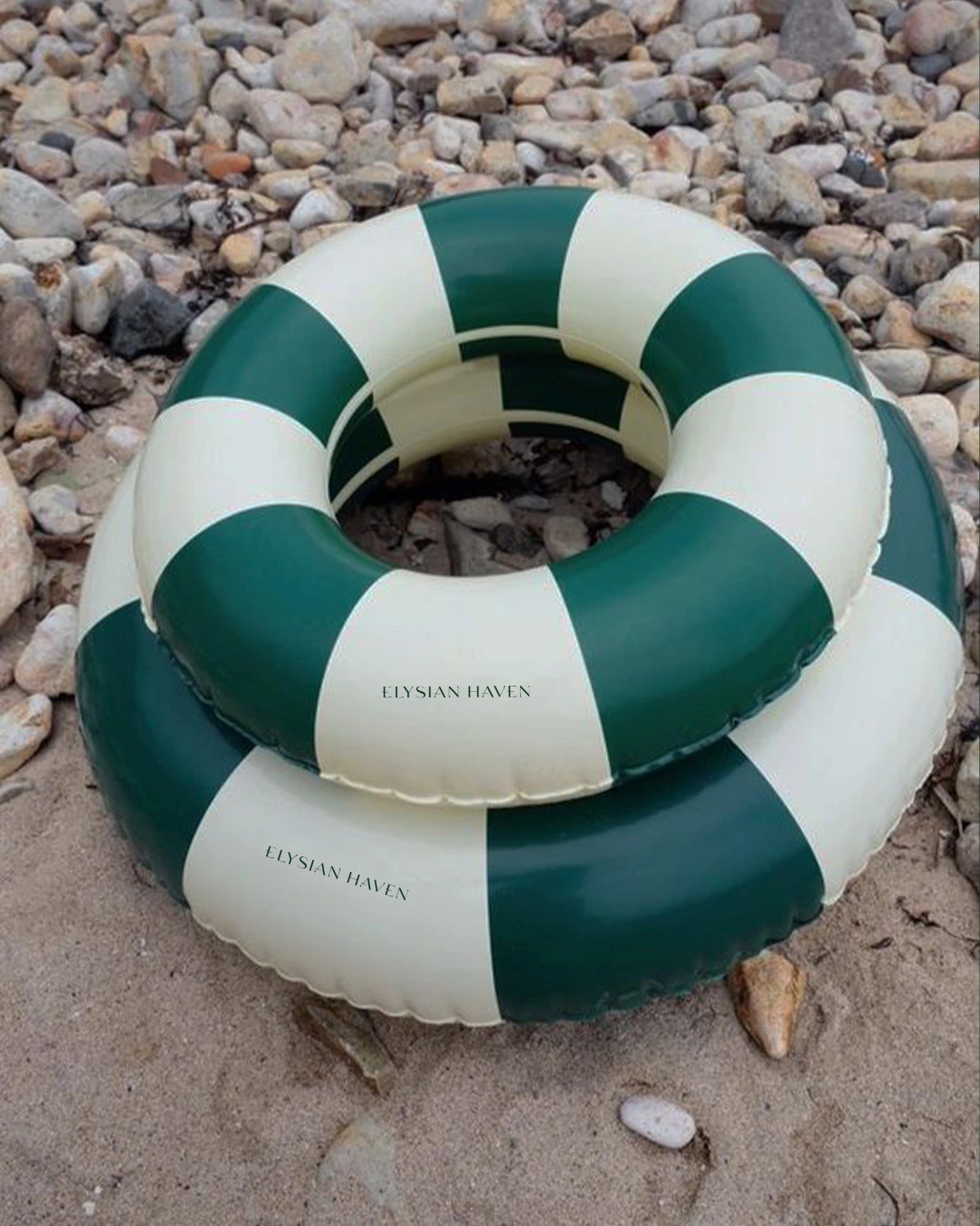 Green and cream Elysian Haven branded pool rings on a pebble shore